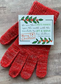 a red pair of oven mitts sitting on top of a wooden table next to a card