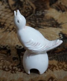 a white bird figurine sitting on top of a rug