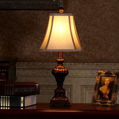 a lamp sitting on top of a wooden table next to a framed photo and books