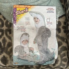 a child's shark costume is shown in the package on top of a leopard print chair