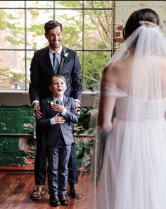 a young boy in a suit and tie standing next to his father at the alter