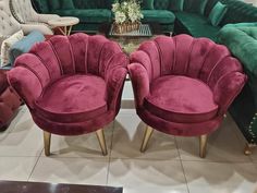 two green velvet chairs sitting next to each other in front of a couch and coffee table