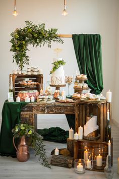 a table topped with lots of food next to a green curtain and candles on top of it