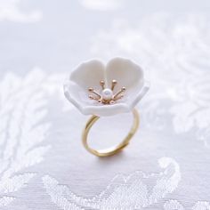 The beautiful plum blossom, who never fears frost and snow, bravely flowers in the coldest seasons, awakening spring and bringing hope. The pure and delicate petals deserve your extra love and care. Ring is made of porcelain flower; gold-plated silver ring and a small freshwater pearl. Material: Handmade porcelain plum blossom; Gold-plated silver ring; Small freshwater pearl. Gold- or silver-plated colour will fade over time. This is a normal result from long-term wear and contact with air. Howe Delicate White Flower Ring, Delicate White Flower-shaped Ring, Delicate White Flower Shaped Ring, White Flower Ring For Promise, Delicate White Flower Ring For Wedding, White Flower Shaped Anniversary Ring, White Birth Flower Ring For Wedding, Nature-inspired White Flower Ring, White Birth Flower Wedding Ring