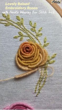 a close up of an embroidered flower on a piece of cloth with thread and needles