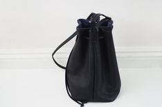 "This bucket bag features soft black leather, cotton lining and a drawstring closure. Carry your phone, a wallet, keys and small items in this bag. Details: -Dimensions: 10.5\" length (top to bottom), 13.5\" opening top width, 6\" depth, 7.5\" X 6\" base (bottom) -Shoulder strap measures approx. 45-50\" total (shoulder strap is adjustable) -Soft black leather -Cotton lining -One internal pocket Hardware color: -Silver (pictured) -Gold Options: -Real cowhide leather (pictured) -Vegan (fake) leath Daily Use Bucket Bag With Snap Closure, Everyday Leather Handle Pouch Bucket Bag, Everyday Bucket Drawstring Bag With Removable Pouch, Leather Bucket Drawstring Bag For Everyday Use, Everyday Leather Bucket Drawstring Bag, Casual Leather Pouch Bucket Bag, Soft Leather Drawstring Bag For Daily Use, Casual Soft Leather Bucket Bag, Daily Use Soft Leather Drawstring Bag