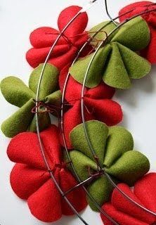 red and green felt flowers are arranged in a circle on a white surface with wire