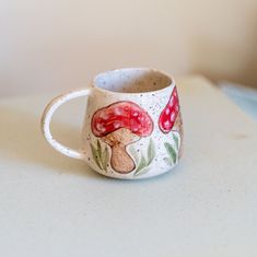 a ceramic cup with mushrooms painted on it