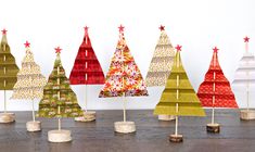 paper christmas trees are lined up in rows on a table with wooden dows and pegs