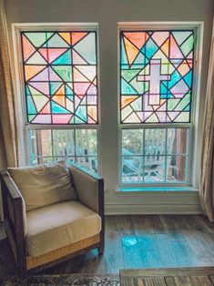 a living room filled with furniture and two large windows covered in colorful stained glass panels