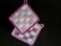 two pink and white crocheted dishcloths on a black surface with one in the center