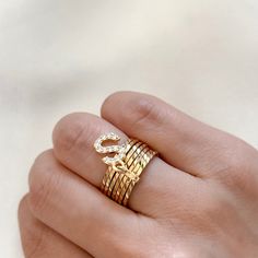 Each of the seven stacked rings represents a layer of strength, unity, and balance. Personalize the ring with an initial letter charm. Together, they symbolize the power of connection. Please note that this ring runs small, and you must size up for the perfect fit. 14k Gold Filled Sizes: 6, 7, 8, 9, 10 Ring Width: 9.5mm Initial Letter Diameter: 17mm x 1.19mm Hypoallergenic Water resistant & tarnish free Nickel & lead free Adjustable Stackable Initials Rings As Gift, Stackable Initial Ring, Fine Jewelry Yellow Gold Stackable Initial Ring, Modern Stackable Initial Ring, Adjustable Stackable Initial Ring, Cz Necklace, Initial Ring, Cz Earrings, Letter Charms