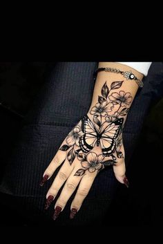 a woman's hand with tattoos on it and flowers in the middle of her arm