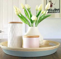 white tulips are in a vase on a tray