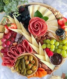 an assortment of cheeses, fruits and meats arranged in a circle on a table