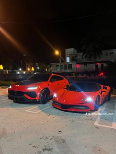 two red sports cars parked next to each other in a parking lot at night time