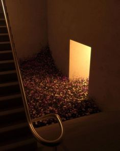 an open door in the corner of a room with flowers on the floor and stairs leading up to it