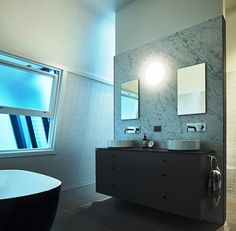 a bathroom with two sinks and a bathtub next to a window in the wall