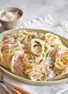 pasta with ham and parmesan cheese on a plate next to utensils