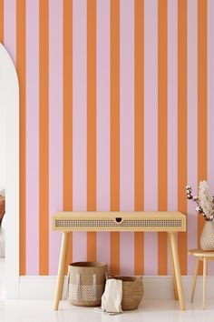 an orange and pink striped wallpaper in a living room with two small wooden tables