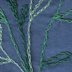 some green thread is on top of a blue cloth and it looks like they have been stitched together