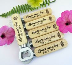 four personalized bottle openers with names and date printed on them next to flowers