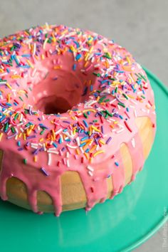 a donut with pink frosting and sprinkles on a green plate