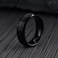 a black wedding ring sitting on top of a bed