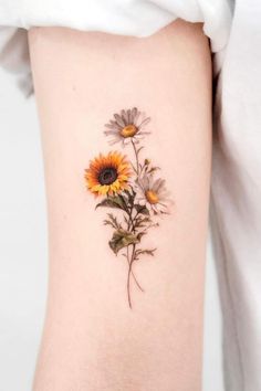 a sunflower tattoo on the right side of the thigh, with leaves and flowers growing out of it