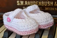 a pair of crocheted baby shoes sitting on top of an old piano keyboard