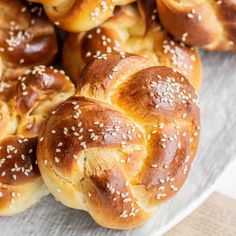 bread rolls with sesame seeds are on a white platter, ready to be eaten