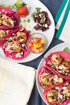 two plates filled with tacos and salads on top of a blue table cloth