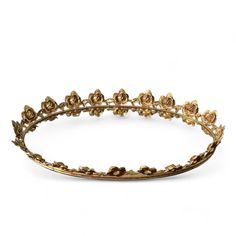 a gold tiara with flowers and leaves on the side, set against a white background