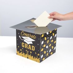 Add this clever card box to your graduation party supplies must-haves! Both functional and decorative, this card box gives graduation party guests a secure place to drop off cards for the graduate while also adding to the graduation theme of the party. Shaped like a graduation cap, this card box will hold a large number of cards and make it easier for the graduate to keep them all in one place. Cardstock. 10" x 10" x 10" box with 13" x 13" lid. Simple assembly required. Graduation Party Card Box Ideas, Grad Party Card Box Ideas, Graduating Elementary School, Card Box Graduation, Graduation Cap Card, Party Card Box, Graduation Card Box, Gold Card Box, Grad Decor