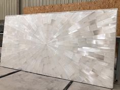 a large white marble slab in a warehouse with plywood walls and flooring behind it