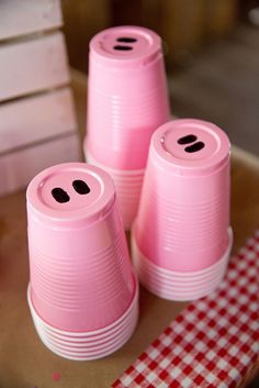 three pink plastic cups sitting on top of a table