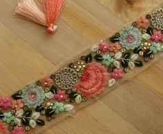 a piece of cloth with flowers and beads on it next to a tassell