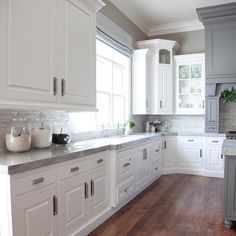 a kitchen filled with lots of white cabinets and counter top space next to a window