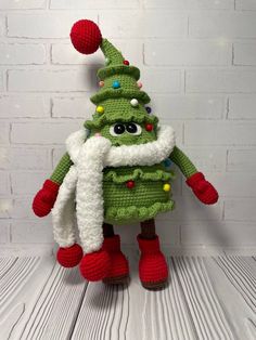 a crocheted christmas tree with red boots and a white scarf on it's head