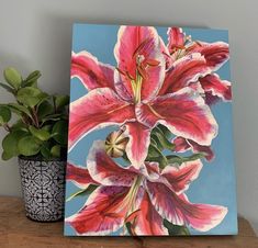 a painting of pink flowers on a table next to a potted plant