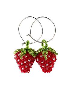 two red strawberries with green leaves on them are hanging from hoop earrings in the shape of fruit