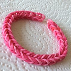 a pink braided bracelet laying on top of a white sheet