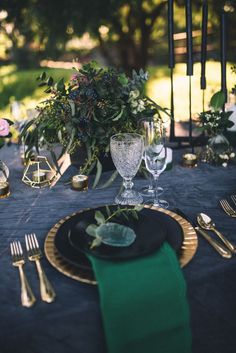 the table is set with black and gold plates, green napkins, and silverware