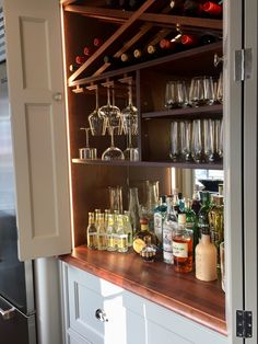 an open cabinet filled with lots of bottles and glasses