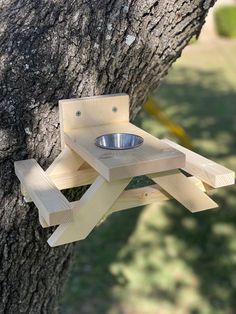 a dog feeder attached to the side of a tree with a bowl in it's holder