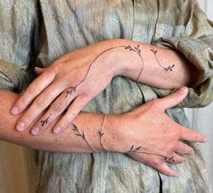 two hands holding each other with tattoos on them