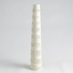 a tall white vase sitting on top of a table