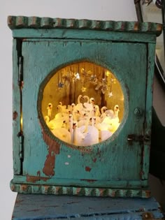 an old blue clock with white swans in the center and lights on it's sides