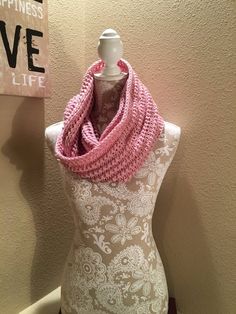 a white mannequin with a pink crochet scarf on it's neck