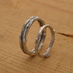 two silver rings sitting on top of a wooden table